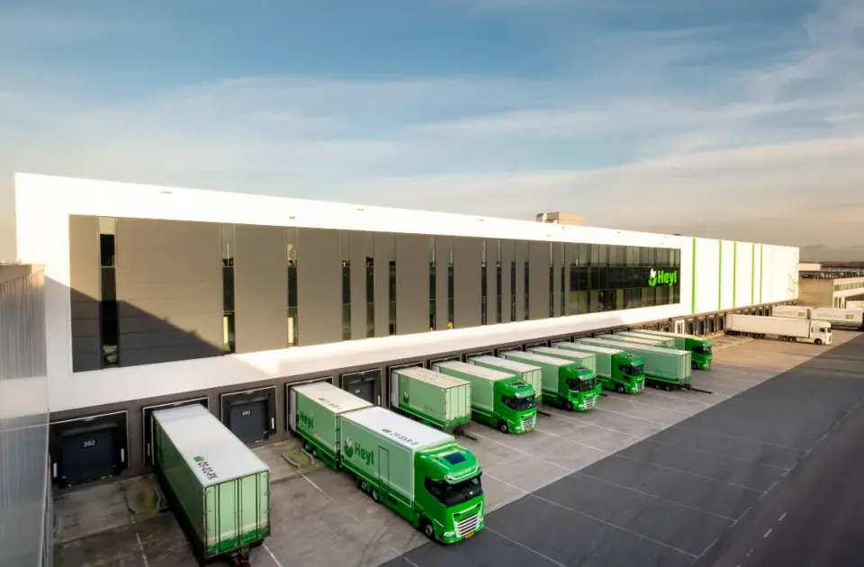 Groene vrachtwagens aan de laadperrons van het distributiecentrum van W.K. Heyl